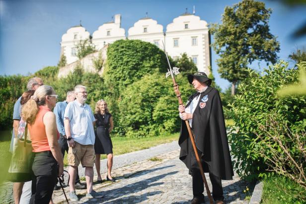 Ernest Zederbauer führt als Nachtwächter in traditioneller Kleidung eine Gruppe Besucher durch Weitra vor dem historischen Schloss.