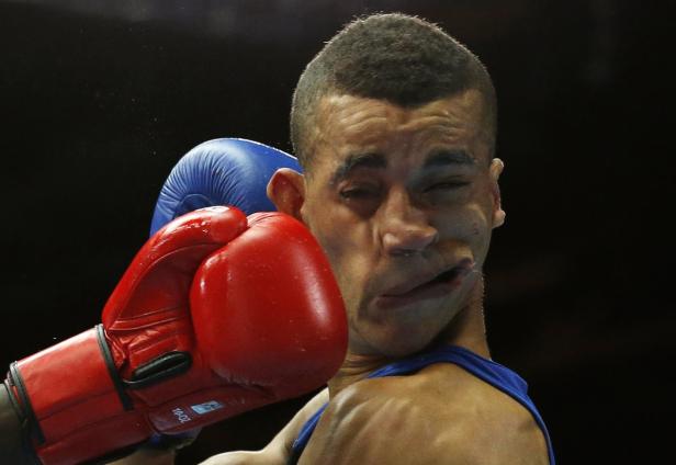 Ein Boxer wird von einem roten Boxhandschuh im Gesicht getroffen.