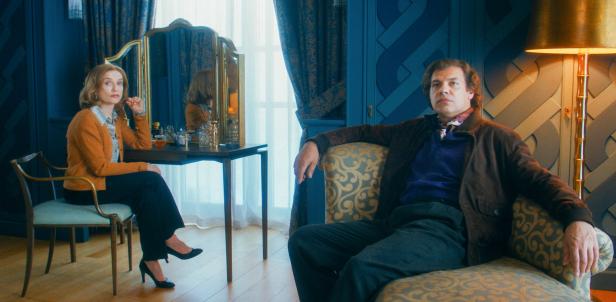 Isabelle Huppert und Laurent Lafitte sitzen in einem eleganten Raum.