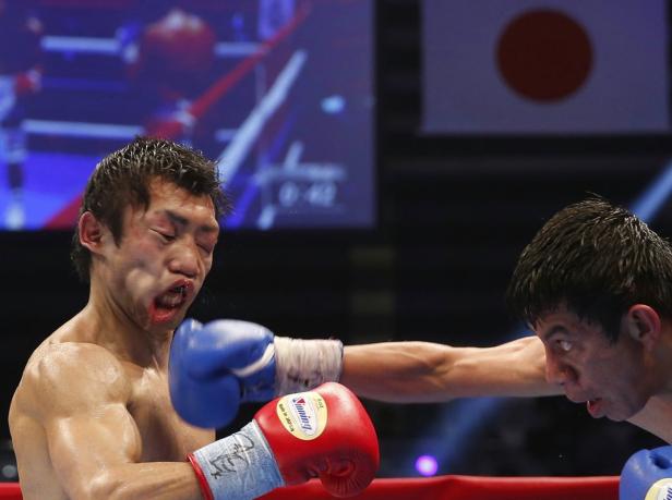 Ein Boxer wird während eines Kampfes im Gesicht getroffen, im Hintergrund die japanische Flagge.