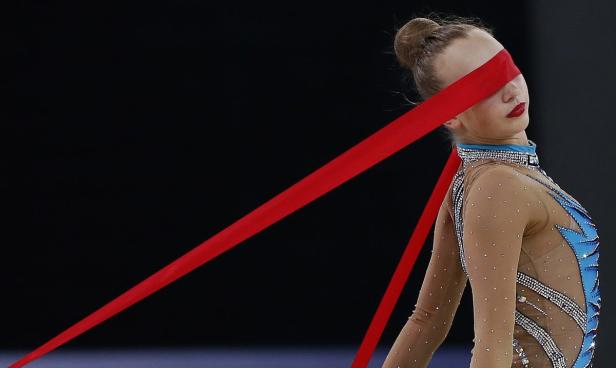 Eine rhythmische Sportlerin mit einem roten Band vor den Augen.