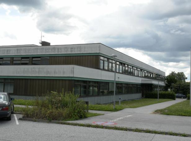 Schulgebäude mit Flachdach und großen Fenstern an einem bewölkten Tag in Hartberg.