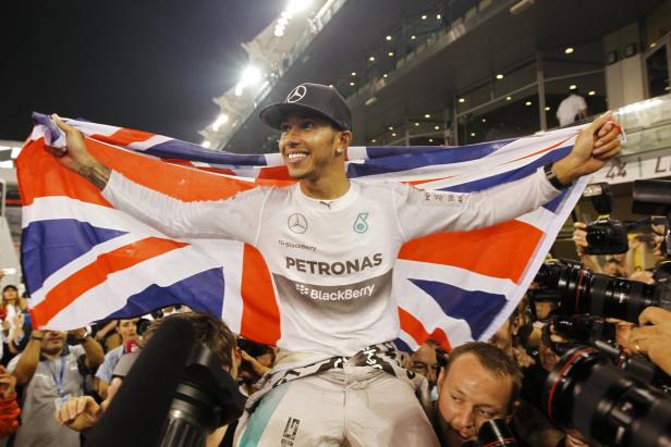 Lewis Hamilton feiert mit der britischen Flagge auf den Schultern seiner Teamkollegen.