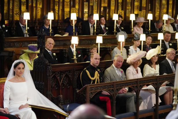 Herzogin Meghan am Tag ihrer Hochzeit in der Kirche. In der ersten Reihe sitzen William, Charles und andere Royals. In der zweiten Reihe sitzt Queen Elizabeth. Der Platz direkt vor ihr ist leer.