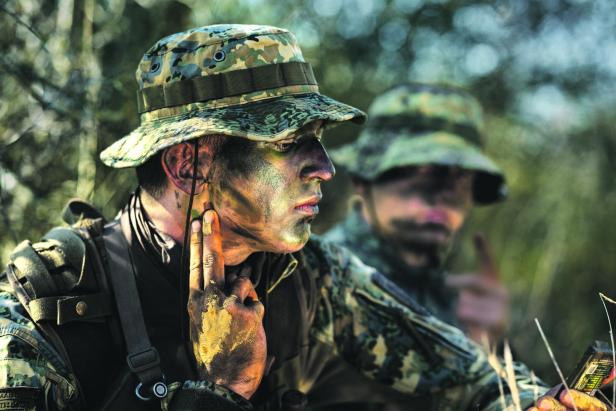 Ein junger Mann in Bundesheer-Montur mit Helm und in Tarnfarben geschminktes Gesicht.