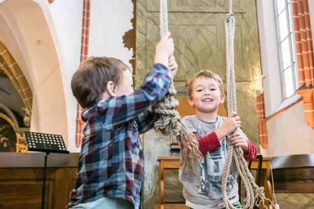 Zwei Kinder läuten lachend die Kirchenglocken und erleben spielerisch das Programm der Langen Nacht der Kirchen in Wien.