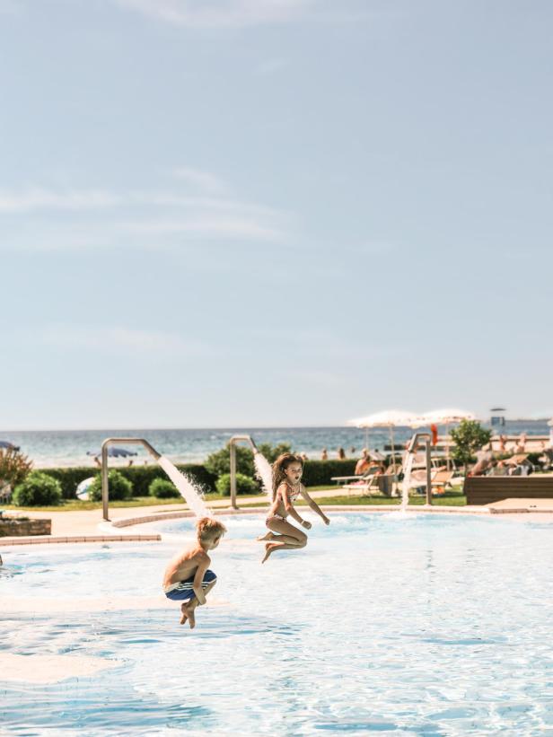 Kinder springen in einen Outdoor-Pool 