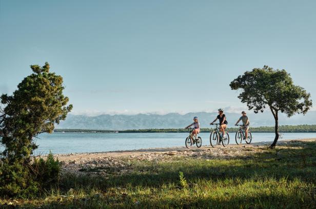 Eine Familie fährt am Meer Fahrrad 