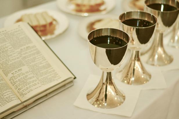 Silberne Kelche mit Messwein und eine aufgeschlagene Bibel stehen bereit, im Hintergrund Teller mit Brot – Symbol für die vielfältigen kirchlichen Rituale der Langen Nacht der Kirchen.