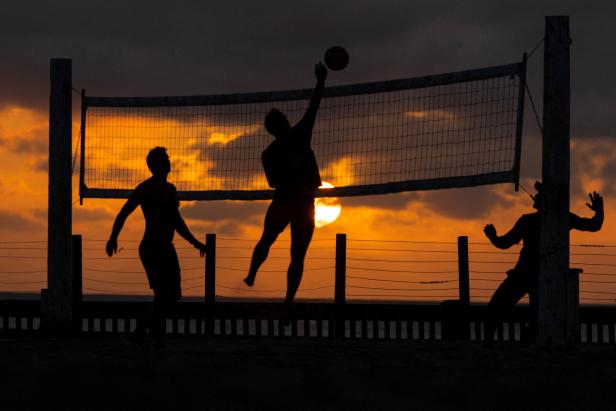 People play volleyball as the sun sets in California