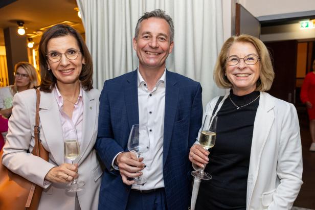 Zwei Teilnehmerinnen und ein Teilnehmer in der Mitte der Netzwerkreihe „Business.Frauen.Zukunft“ stehen lächelnd nebeneinander im Hoxton Vienna.