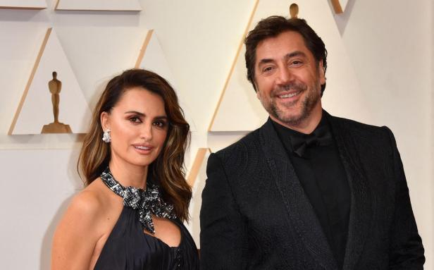 Penélope Cruz und Javier Bardem posieren auf einem Event in eleganter Abendgarderobe.