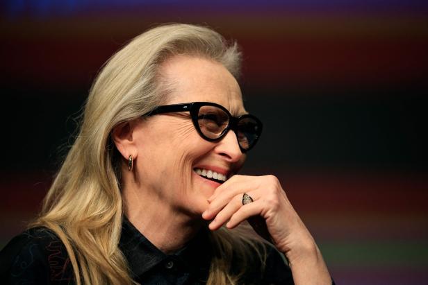 Meryl Streep lächelt mit Brille und hält ihre Hand ans Gesicht.