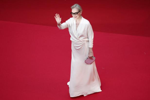 Meryl Streep im weißen Kleid winkt auf dem roten Teppich.