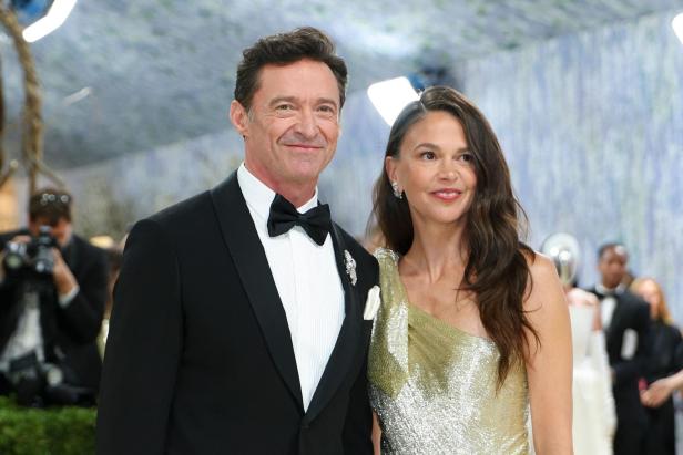 Hugh Jackman und Sutton Foster posieren lächelnd, er im Smoking, sie in einem goldenen Kleid.