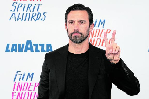 Milo Ventimiglia zeigt das Friedenszeichen vor einem Hintergrund der Spirit Awards.