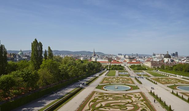 Blick vom Oberen Belvedere über die barocken Gartenanlagen auf die Wiener Innenstadt mit markanten Wahrzeichen wie Stephansdom und Karlskirche.