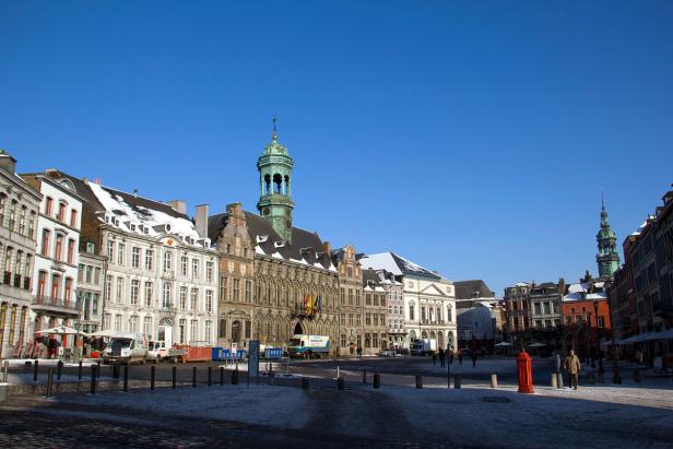 Ein verschneiter Marktplatz mit historischen Gebäuden in Mons, Belgien.