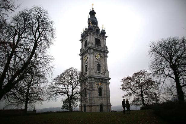 Zwei Personen stehen vor dem Glockenturm von Mons in Belgien.
