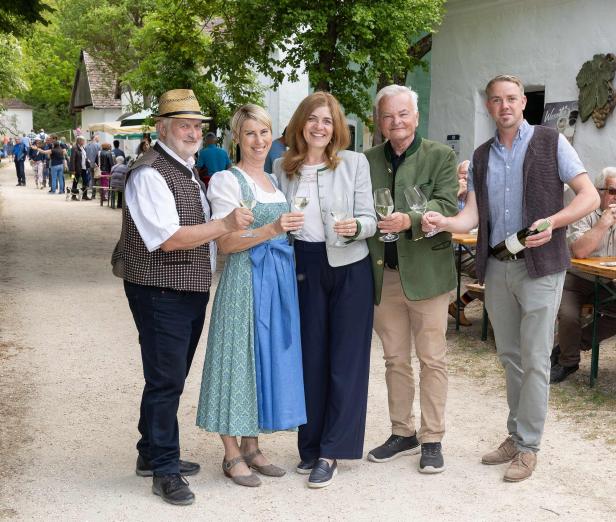 Fünf Personen stoßen mit Weingläsern beim Kellergassenfest im Museumsdorf Niedersulz an.