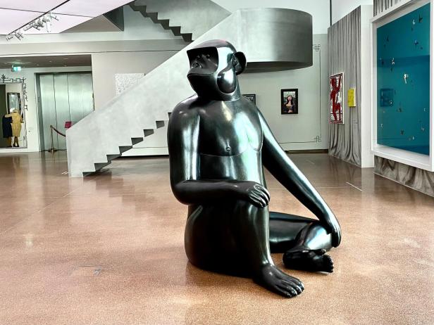 Eine große, schwarze Skulptur eines sitzenden Affen steht im Ausstellungsraum der Heidi Horten Collection, umgeben von moderner Kunst.