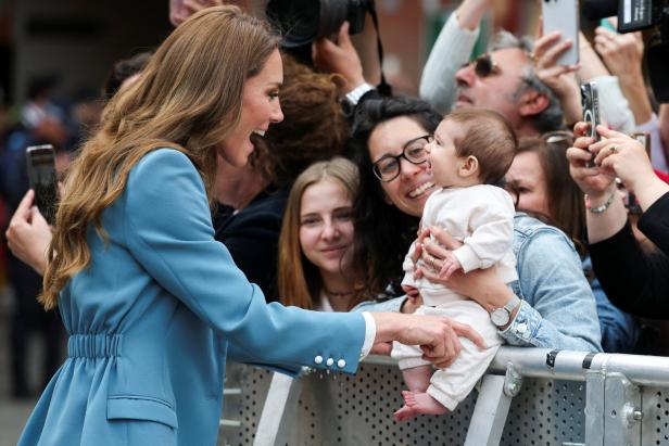 Prinzessin Kate lächelt ein Baby an, das von einer Frau in der Menge gehalten wird.