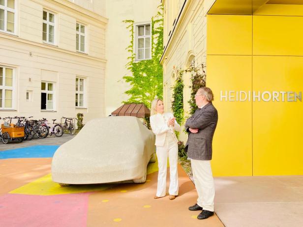 Vor dem Eingang der Heidi Horten Collection steht Gottfried Bechtolds Betonporsche, während zwei Personen im Gespräch sind.