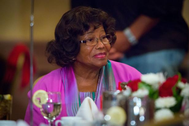 Katherine Jackson sitzt an einem festlich gedeckten Tisch und blickt lächelnd zur Seite.
