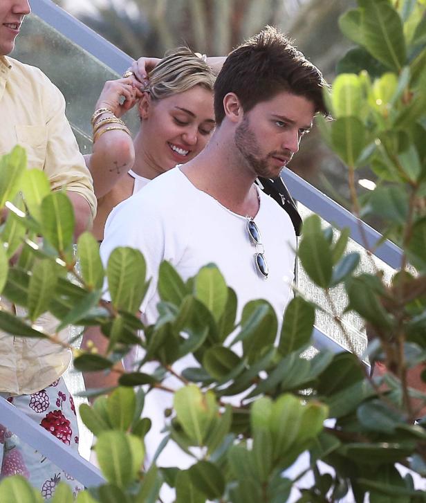 Miley Cyrus steckt einem Mann eine Haarspange ins Haar.