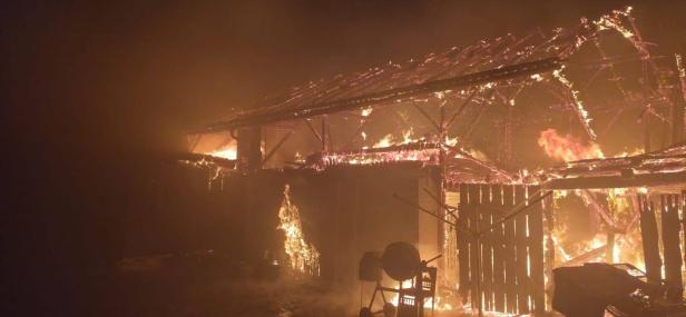 Feuerwehrleute bekämpfen einen Großbrand in einer stark verrauchten Maschinenhalle.