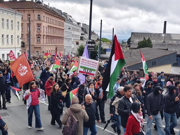 Viele Menschen demonstrieren mit palästinensischen Fahnen und Transparenten auf einer Straße in einer Stadt.