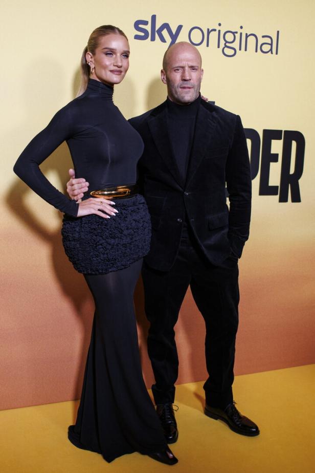 Rosie Huntington-Whiteley und Jason Statham posieren auf einem gelben Teppich.