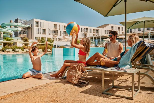 Eine Familie spielt an einem Hotelpool 