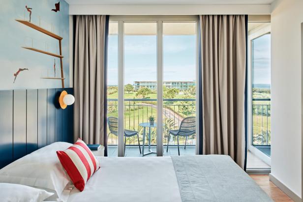 Ein Doppelbett in einem Hotel mit einem Balkon und bodentiefen Fenster