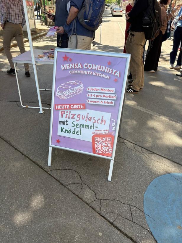 Ein Aufsteller informiert über ein günstiges Pilzgulasch mit Semmelknödel bei einer Community-Küche namens Mensa Comunista.