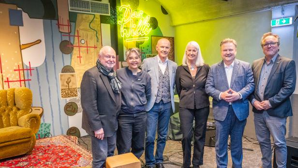 Eine Gruppe von sechs Personen steht vor einer Wand mit dem Schriftzug "Das Willi".