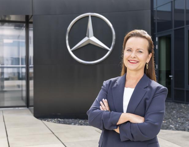 Agnieszka Kühn, CEO   Mercedes-Benz Österreich steht vor einem Mercedes Logo.