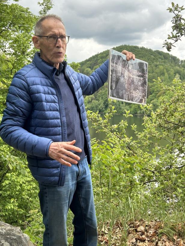 Ein Mann steht im Wald mit einem Bild in der Hand