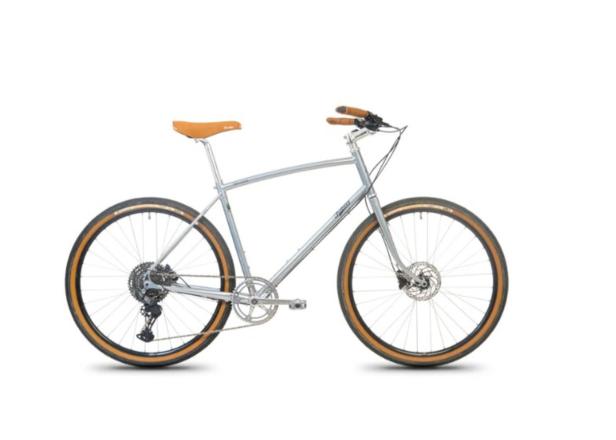 Silbernes Fahrrad mit braunem Sattel und Griffen, dicken Reifen und Scheibenbremsen auf weißem Hintergrund.