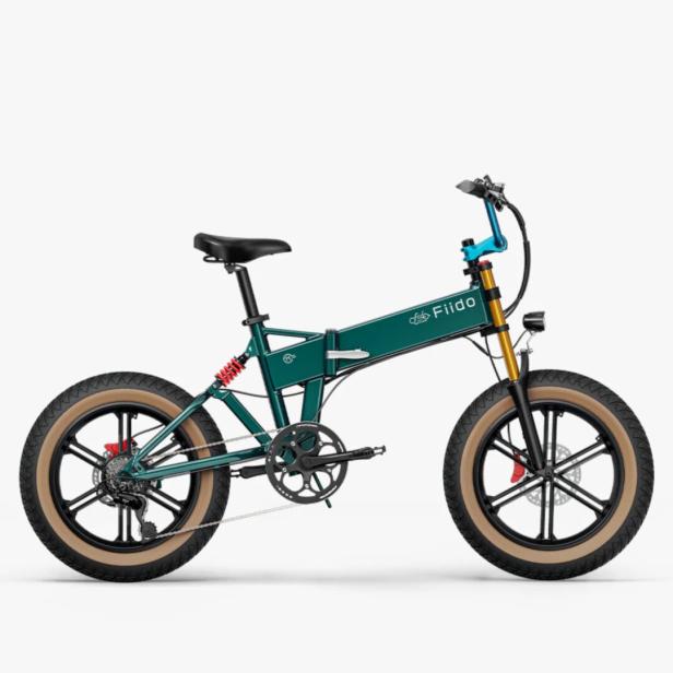 Ein modernes, grünes E-Bike mit dicken Reifen, Federung und schwarzem Sattel steht seitlich auf weißem Hintergrund.