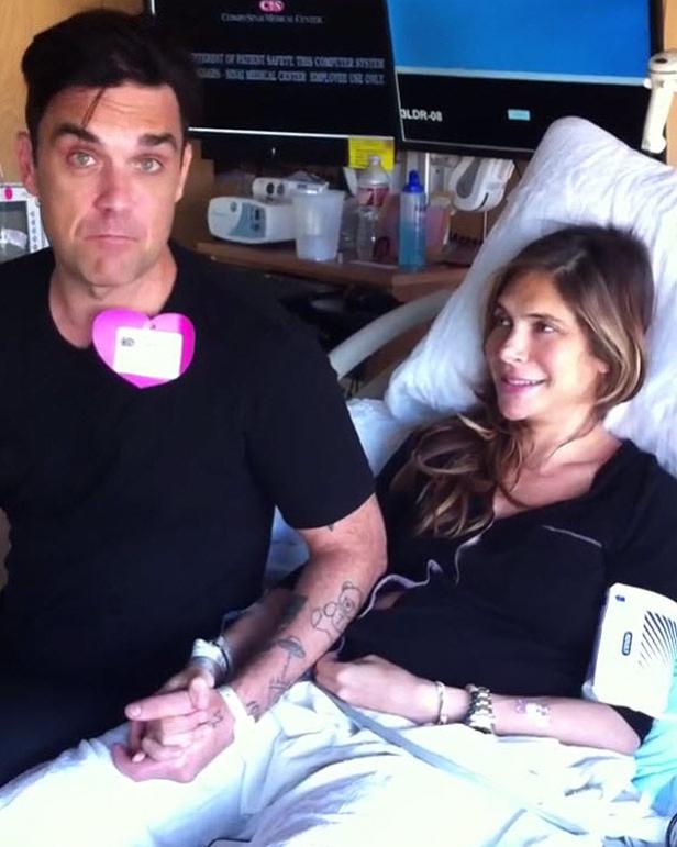 Robbie Williams sitzt mit seiner Frau im Krankenhausbett.