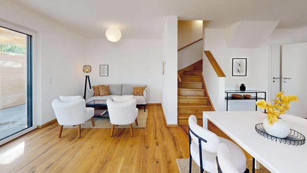 Helles, modern eingerichtetes Wohnzimmer mit Holztreppe und Zugang zur Terrasse.