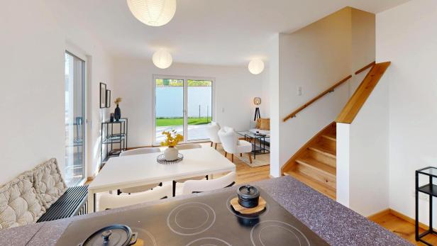 Helles, modern eingerichtetes Wohnzimmer mit Holztreppe und Zugang zur Terrasse.
