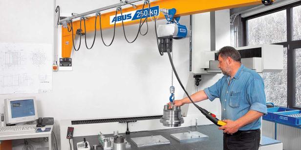 Mitarbeiter bedient einen ABUS-Schwenkkran und hebt ein Metallteil in einer Werkstatt.