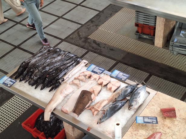 Auf einem Marktstand liegen verschiedene Fischsorten auf Eis, darunter schwarzer Degenfisch und Thunfisch.