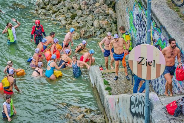 Schwimmerinnen und Schwimmer steigen am Ziel der Schwimmparade Donaukanal aus dem Wasser.