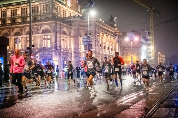 Mehrere Personen laufen für den Vienna Night Run an der Wiener Staatsoper vorbei.