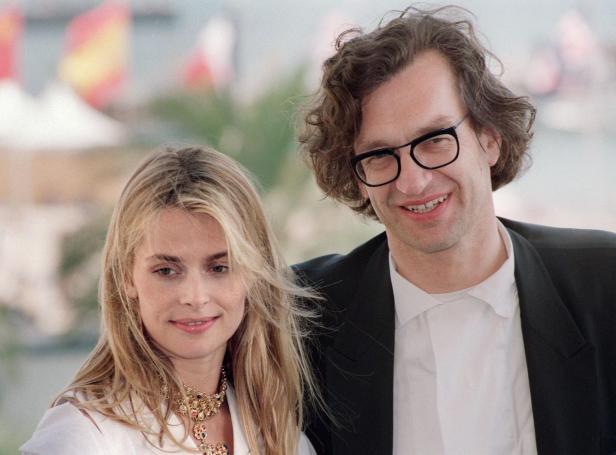 Eine Frau mit blondem Haar und ein Mann mit Brille und lockigem Haar stehen nebeneinander und lächeln.