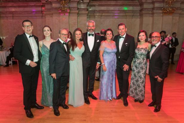 Mehrere elegant gekleidete Gäste posieren gemeinsam im Festsaal des Palais Niederösterreich.