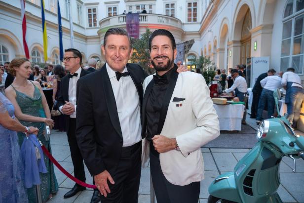 Mehrere elegant gekleidete Gäste posieren gemeinsam im Festsaal des Palais Niederösterreich.